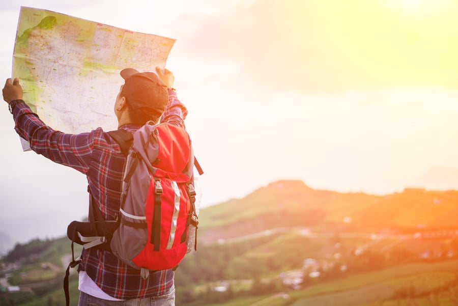 Lost hiker with backpack checks map